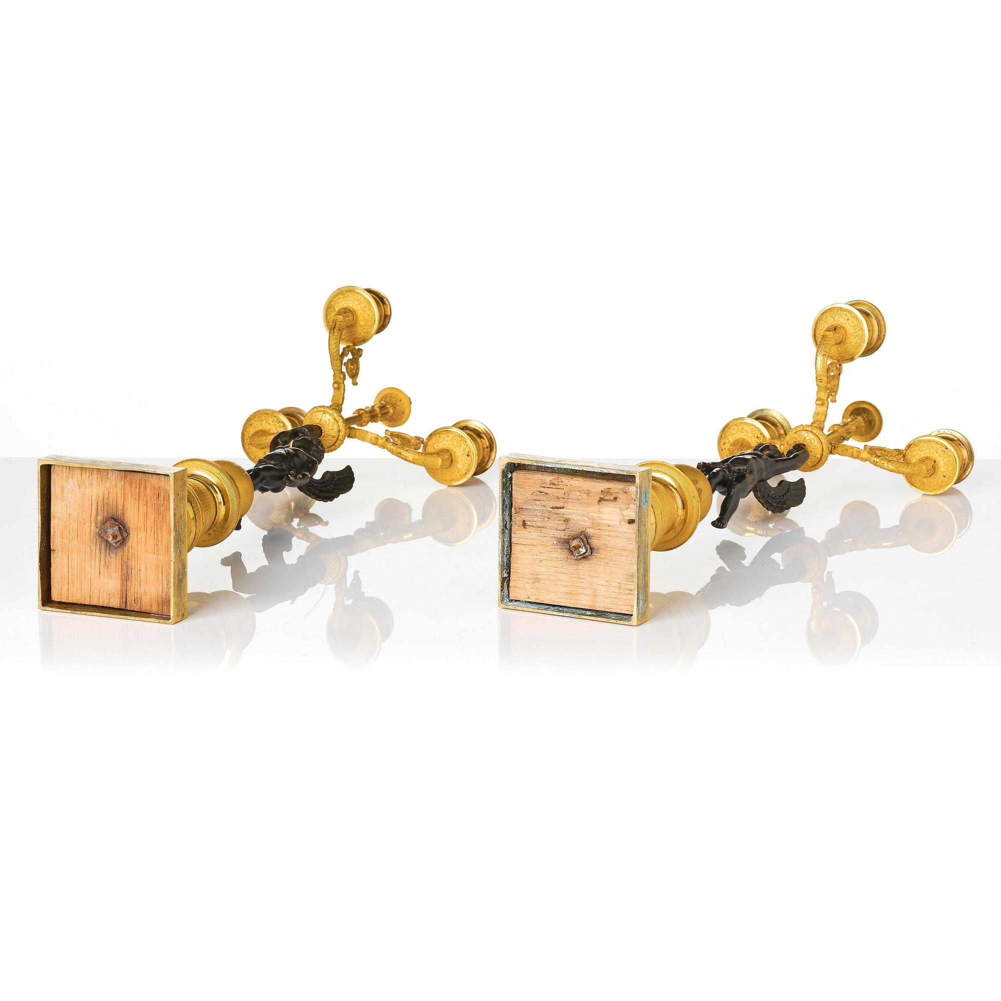 A pair of Empire three light ormolu and patinated bronze candelabra.