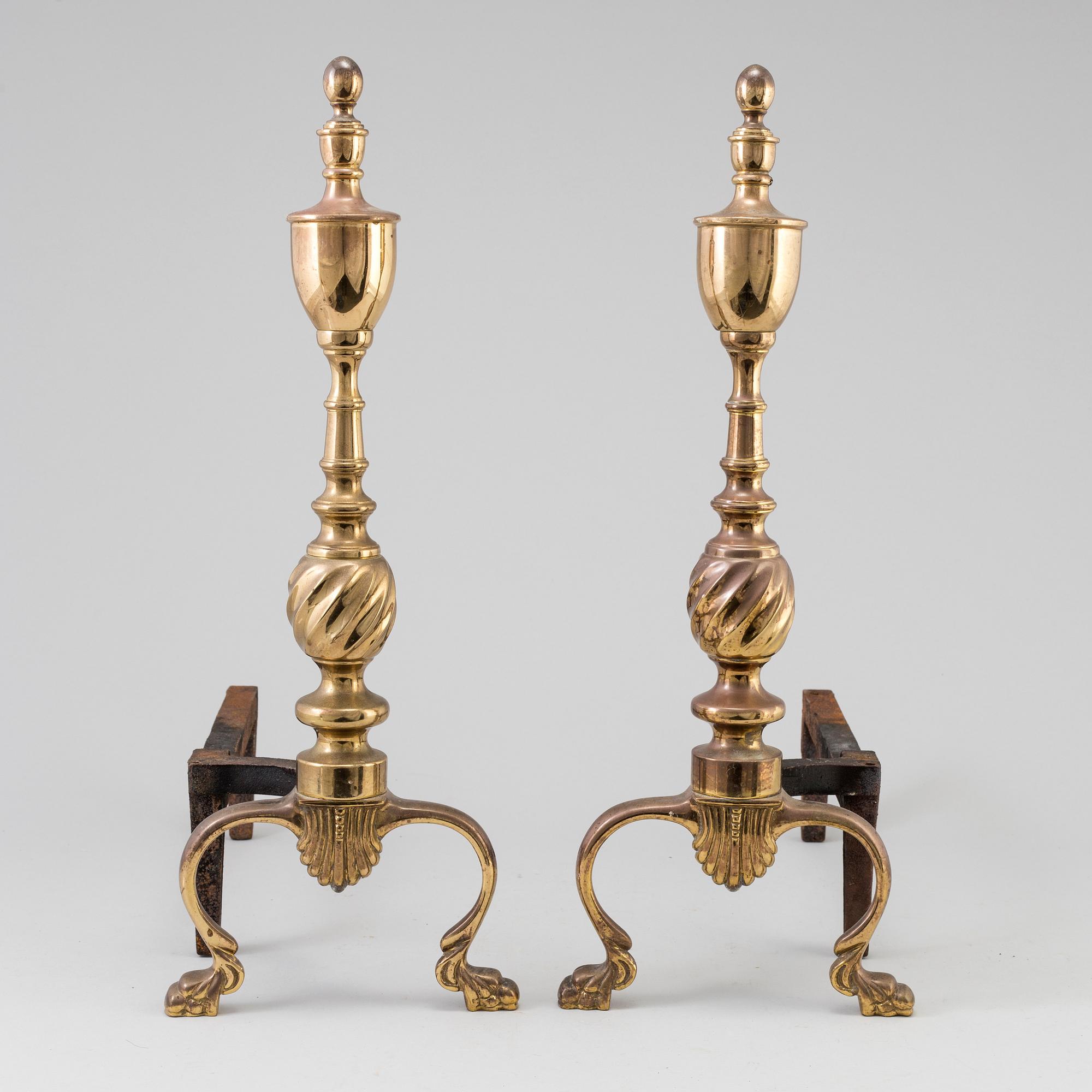 A pair of  ornate brass urn top cast iron fireplace fire dog andirons from around the year 1900.