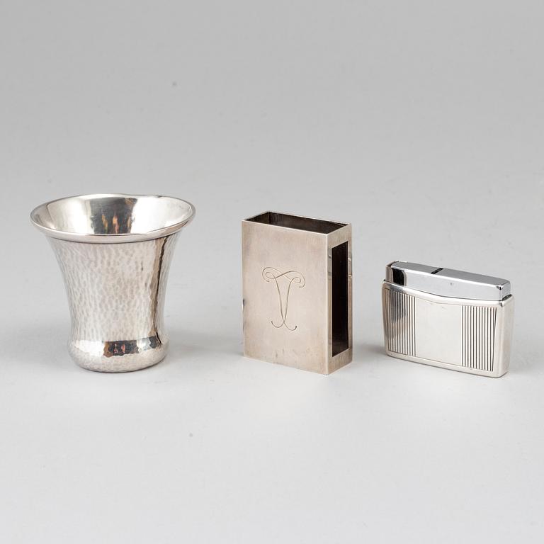 A silver vodkacup, lighter and matchholder.