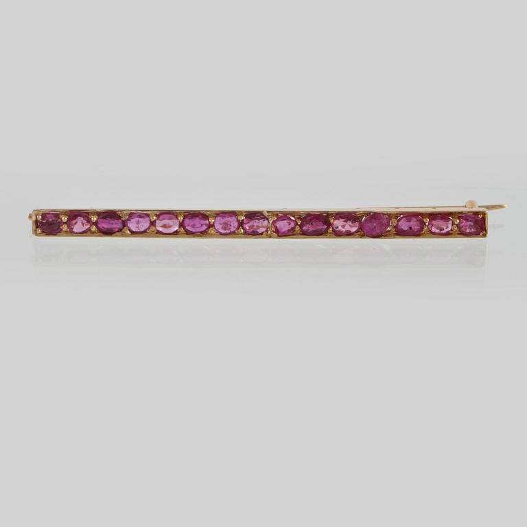 BROSCH, 18K guld med 15 fasettslipade rubiner. Vikt 4,8 gram.