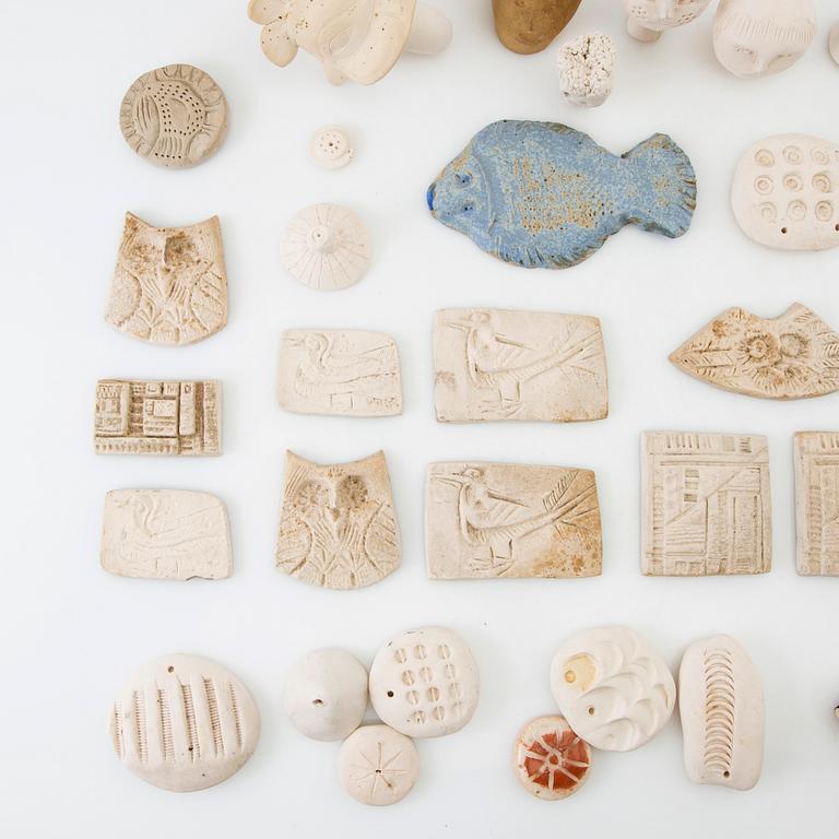 Anita Nylund, ca 39 st. pärlor, plaketter, miniatyrhuvuden mm. Egen verkstad.