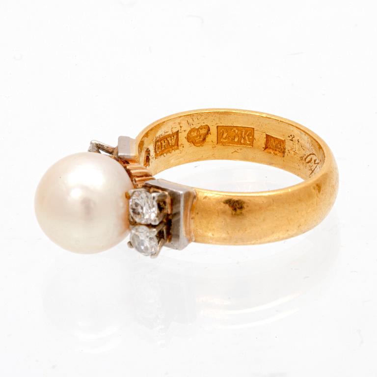 A 23K white and red gold ring with round brilliant cut diamonds and a cultured pearl.