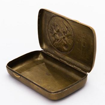 A BRASS FABERGÉ CIGARETTE CASE, 1914-1915.