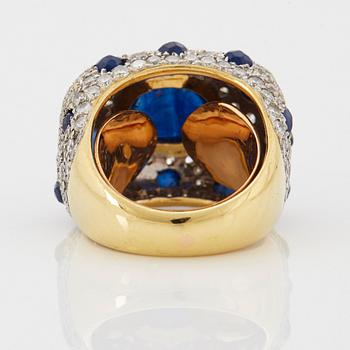 An 18K gold ring set with a cabochon-cut sapphire and round brilliant-cut diamonds and faceted sapphires.