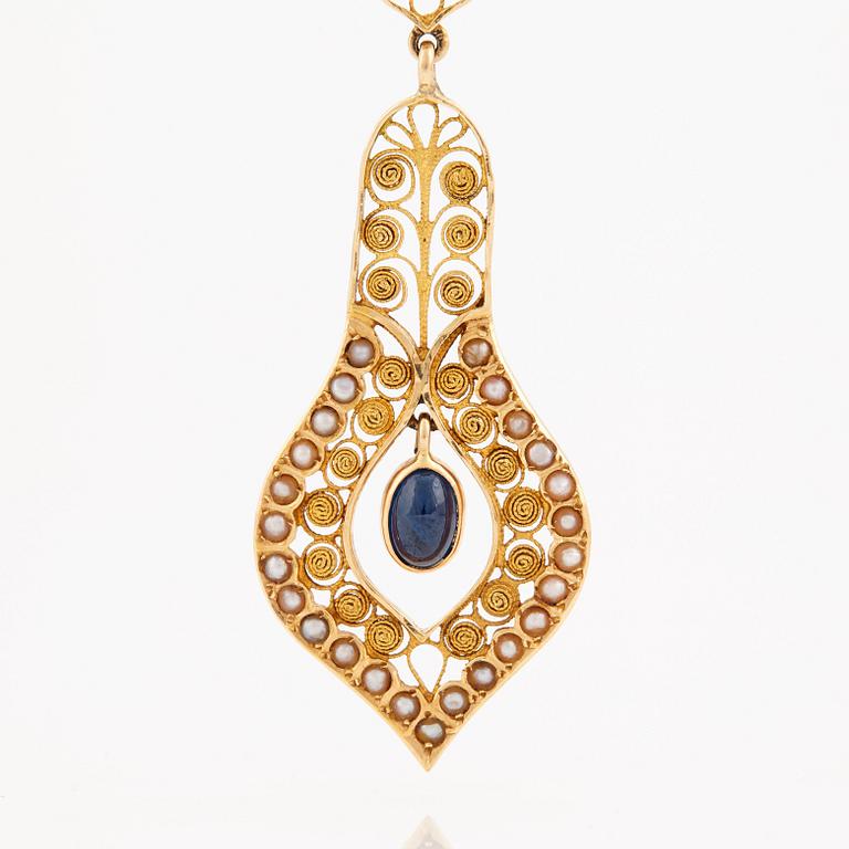 A necklace set with seed pearls, a cabochon cut sapphire, probably another sapphire and filigree work.