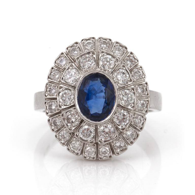 A ring set with an oval, mixed-cut sapphire and round, brilliant-cut diamonds.