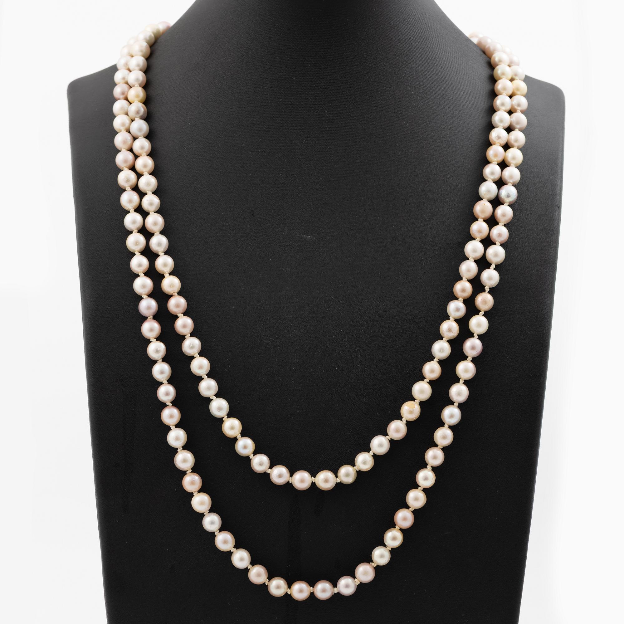 Long cultured pearl necklace with an 18K white gold clasp set with emeralds.
