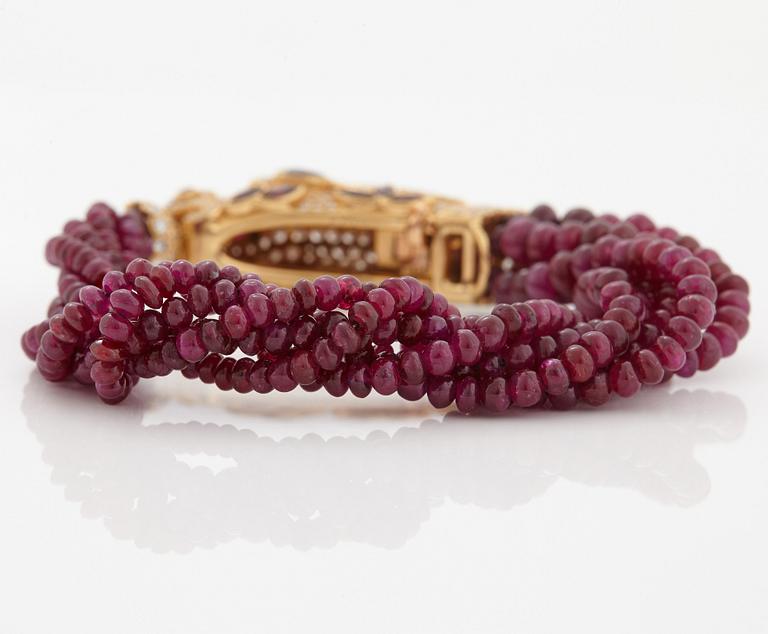 A Cartier chimera head bracelet in 18K gold set with round brilliant-cut diamonds and faceted rubies.