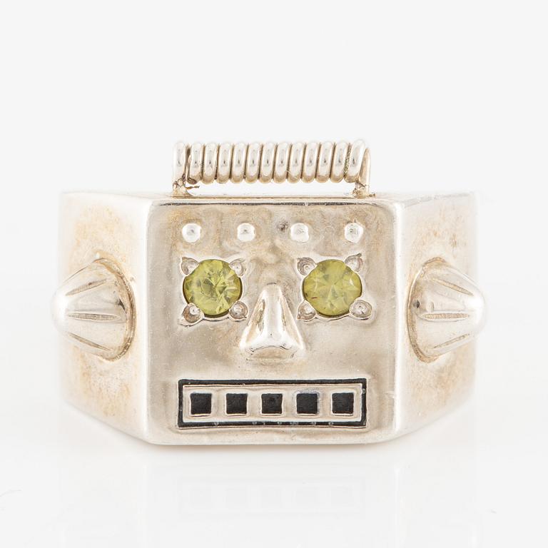 Maria Nilsdotter ring i form av ett robothuvud, sterlingsilver och gröna ögon.