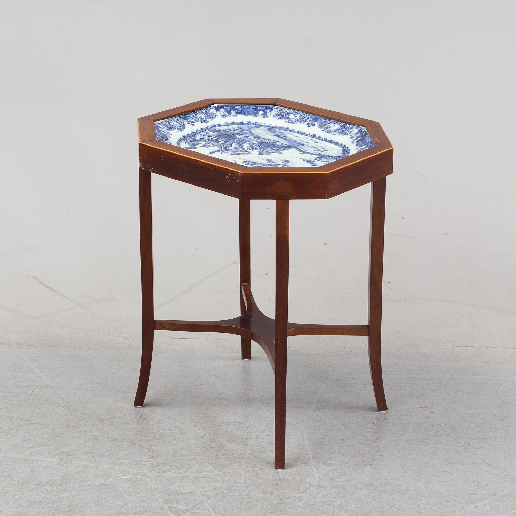 A mahogany veneered table with a Chinese blue and white porcelain charger, Qianlong (1736-95).