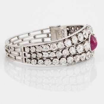 An 18K white gold bangle set with a cabochon-cut ruby and old-cut diamonds.