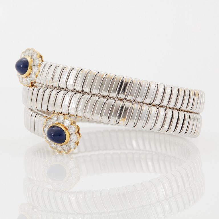 An 18K gold bangle set with cabochon-cut sapphires and round brilliant-cut diamonds.