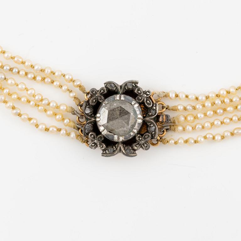 A five-strand pearl necklace with a rose-cut diamond silver and 14K gold clasp with small rose-cut diamonds.