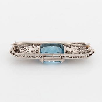 An 18K white gold brooch set with a faceted aquamarine and round brilliant- and rose-cut diamonds.