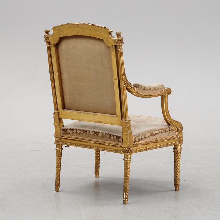 A gilt Louis XVI style armchair from around the year 1900.