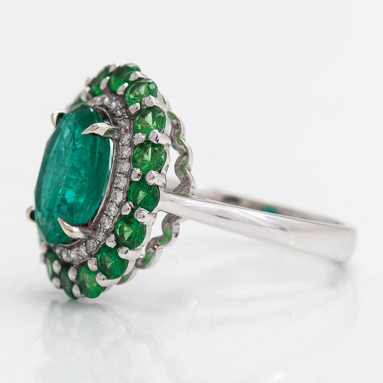 A 14K white gold ring with an emerald  2.33 ct, tsavorites 1.20 ct and diamonds ca 0.14 ct. With IGI certificate.