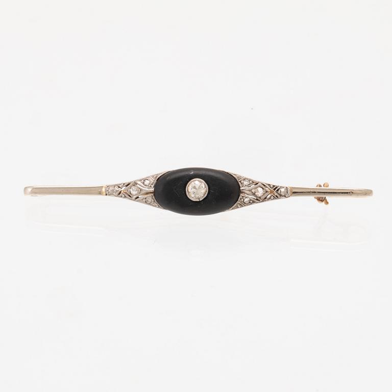 A 14K white and red gold brooch set with round brilliant-cut and rose-cut diamonds and a black stone.