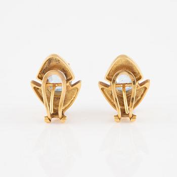 A pair of 18K gold earrings with faceted blue stones.