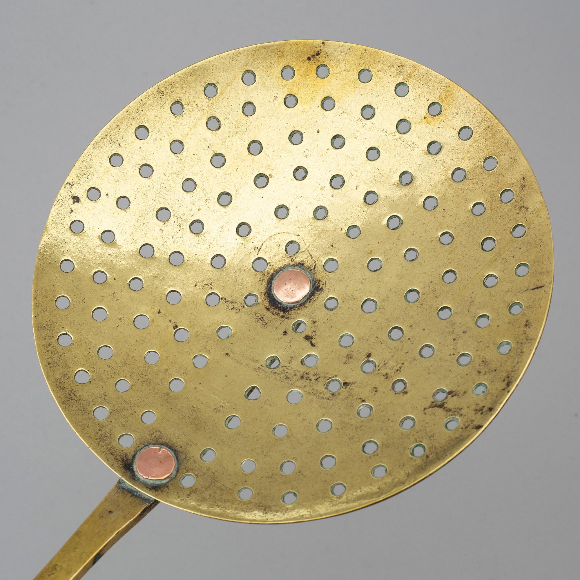 An 18th century brass strainer.