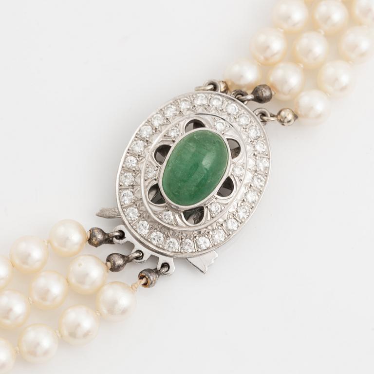 Three-row pearl necklace with cultured pearls, clasp with cabochon-cut emerald and brilliant-cut diamonds.