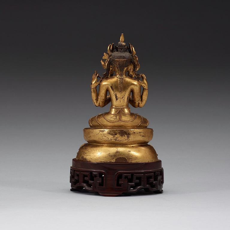 A gilt copper alloy figure of Sukhavati Avalokiteshvara seated on a high lotus base, Tibet, 15th/16th Century.
