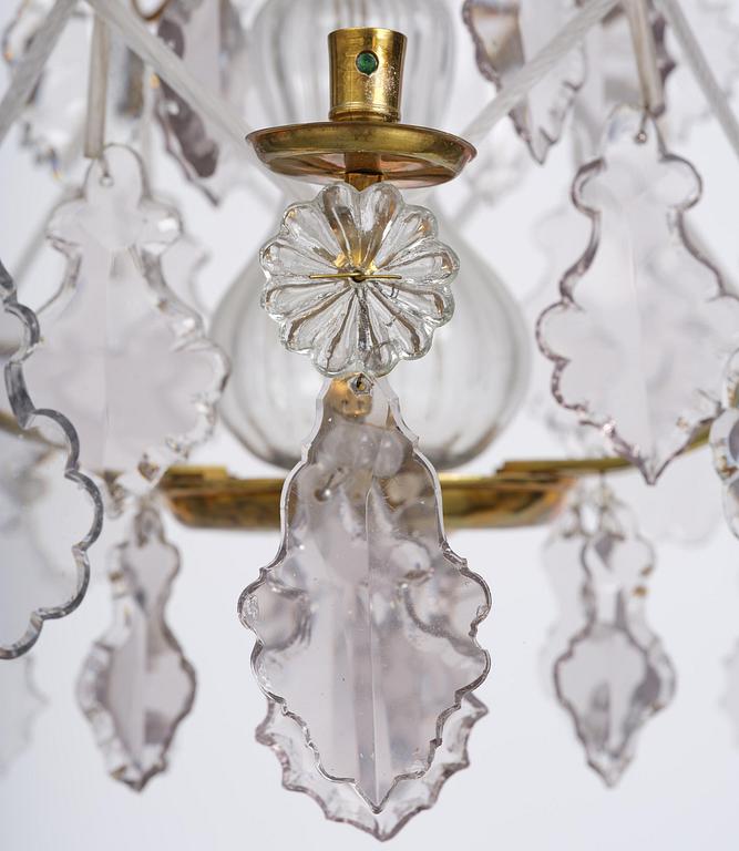 A near pair of rococo-style gilt brass and cut glass six-branch chandeliers, 19th century incorporating older elements.