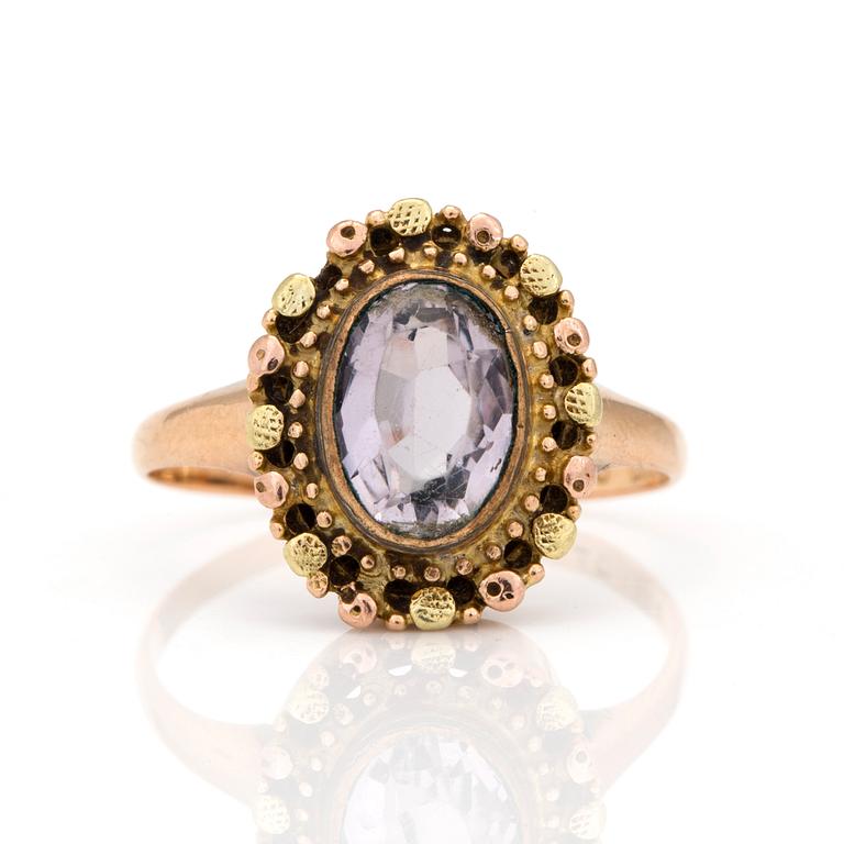 A ring with an oval, mixed-cut amethyst.