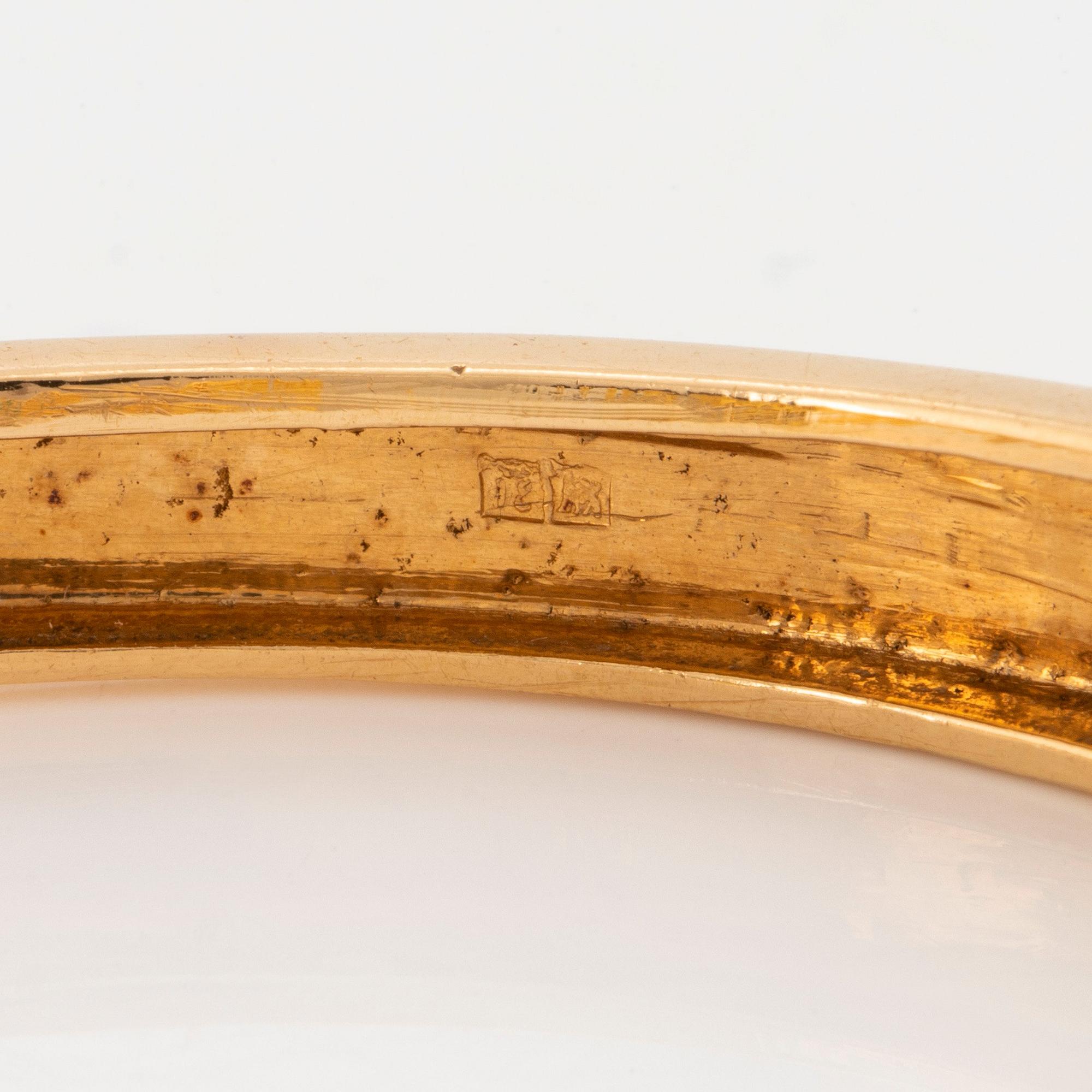 An 18K gold bangle set with round brilliant-cut diamonds, sapphires, emeralds and rubies.