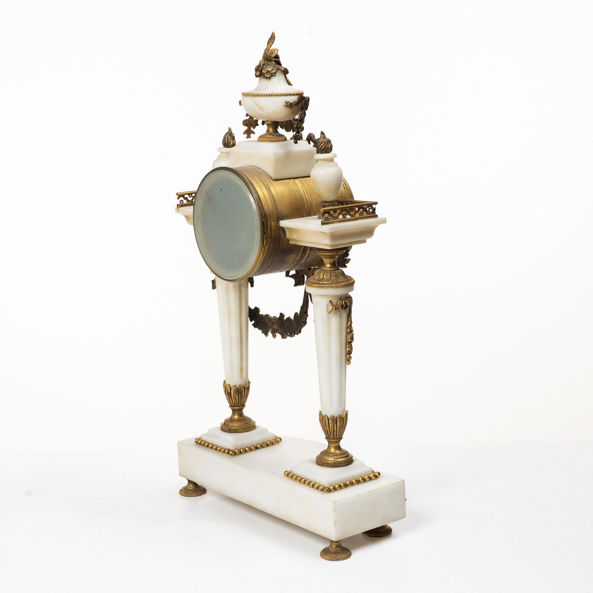 A Louis XVI-style mantle clock and a pair of candelabras. Early 20th century.