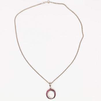 A 14K gold and silver necklace with a moon stone, rubies and a red glass stone.