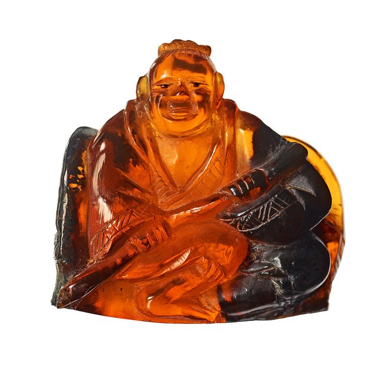 An amber figurine of a sitting man with baskets, Qing dynasty (1644-1912).
