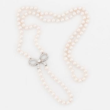 526. A cultured pearl necklace with a 14K white gold bow pendant set with round brillliant-cut diamonds.