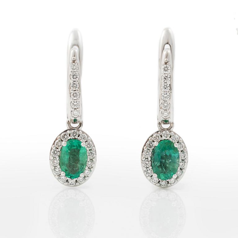 Ett par örhängen med fasettslipade smaragder och runda briljantslipade diamanter.