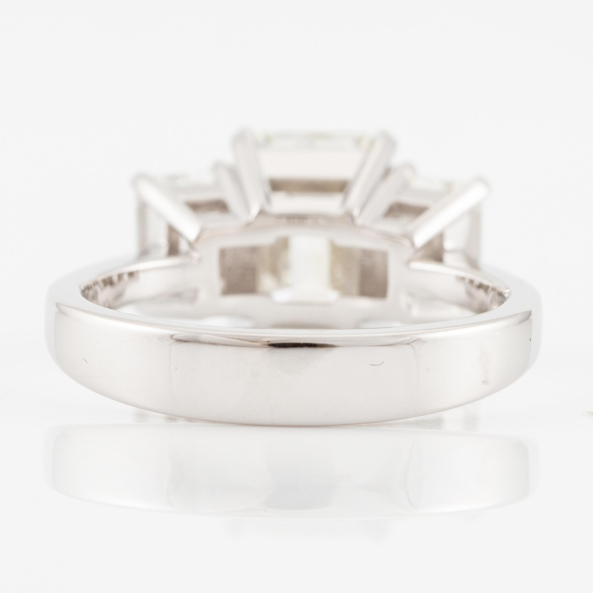 An 18K white gold ring set with three emerald-cut diamonds.