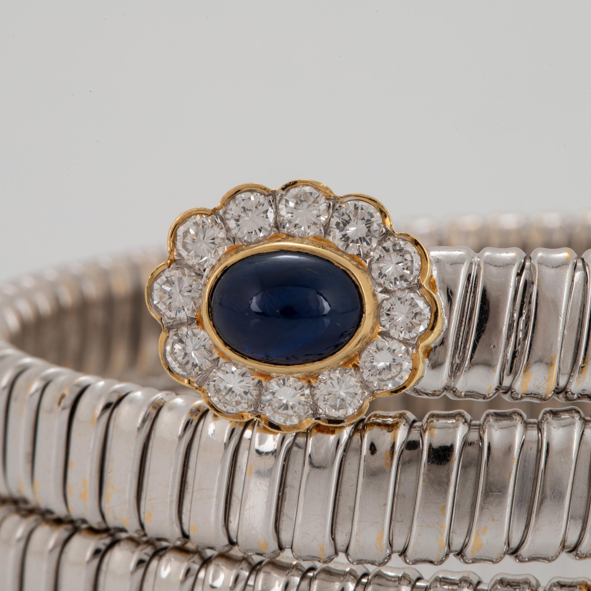 An 18K gold bangle set with cabochon-cut sapphires and round brilliant-cut diamonds.
