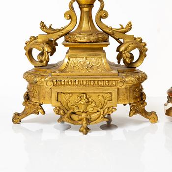 A mantle clock and a pair of candelabra, Louis XVI style, ca 1900.