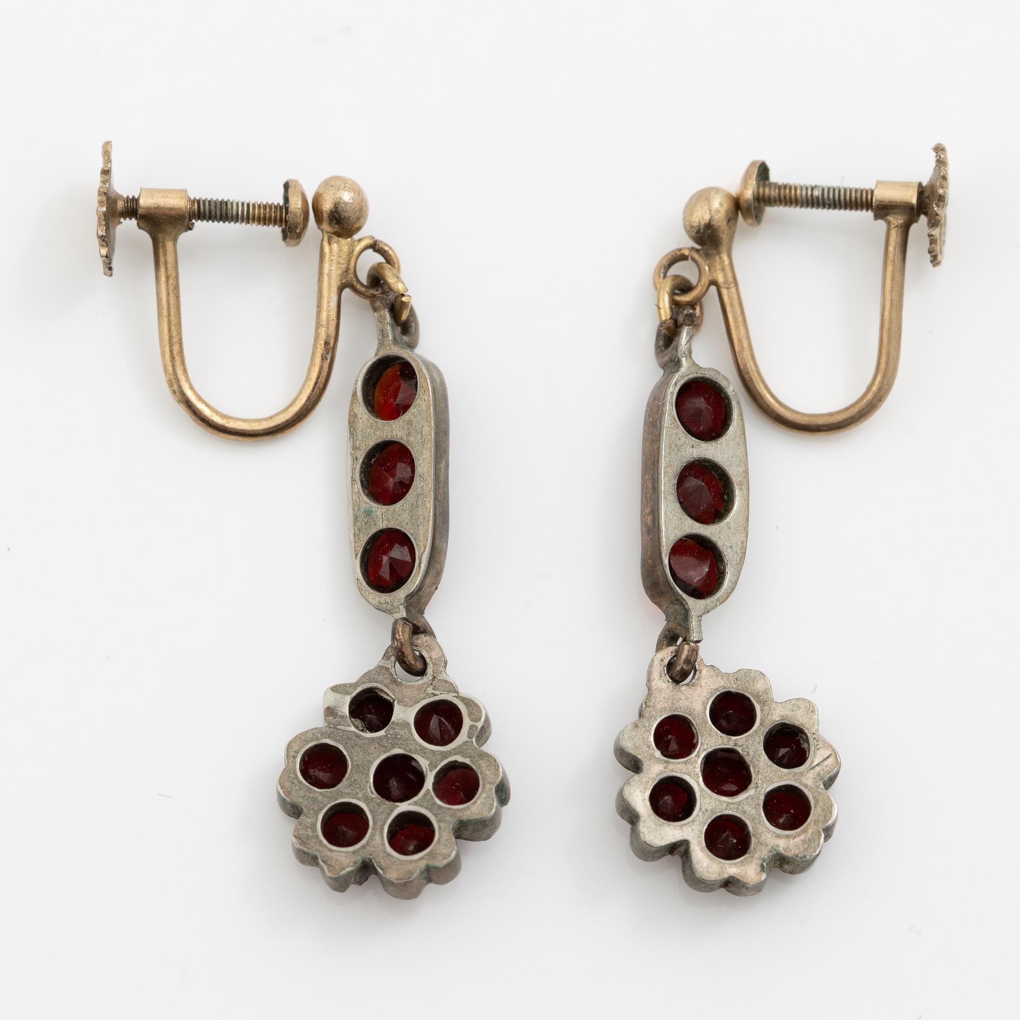 Garniture, necklace/bracelet and earrings in silver with garnets in the form of floral motifs, around the turn of the 20th century.