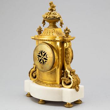 A late 19th century pendulum clock and a pair of candelabras.