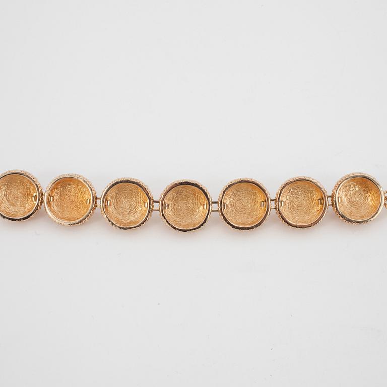 CHRISTIAN DIOR, a gold colored metall braclet with decorative glass stones.
