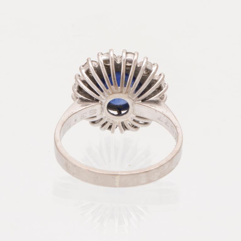 An 18K white gold ring set with a cabochon cut sapphire and round brilliant cut diamonds.