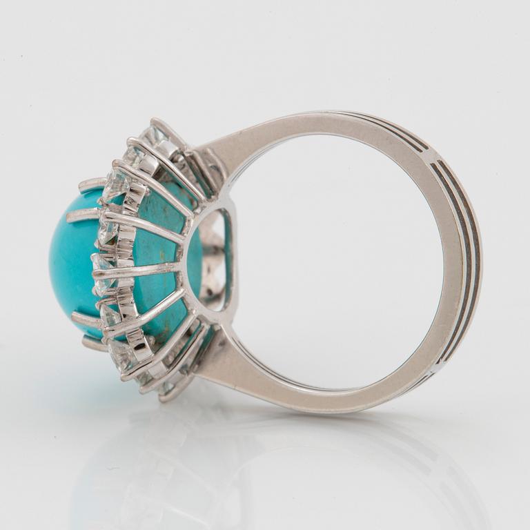 An 18K white gold ring set with a cabochon-cut turquoise and round brilliant-cut diamonds.