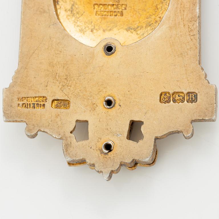 A jeton and pin, in gilded silver and 9 ct gold respectively.