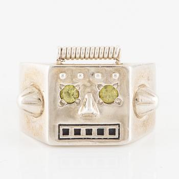 Maria Nilsdotter ring in the form of a robot head, sterling silver and green eyes.