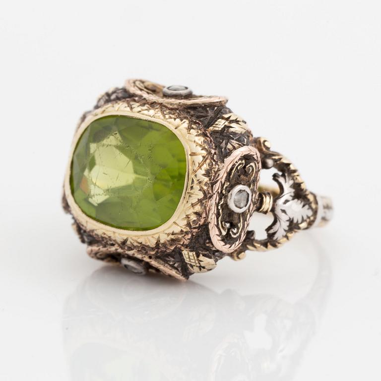 A silver and gold ring set with a faceted peridot and rose-cut diamonds.