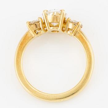 A ring in 18K gold with an oval brilliant-cut diamond and two round brilliant-cut diamonds.