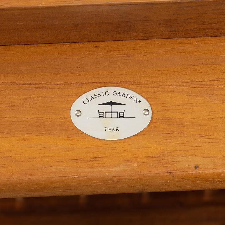 A pair of teak deck chairs and a table, 21st Century.