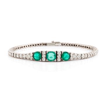 A platinum bracelet set with emeralds and round brilliant-cut diamonds.