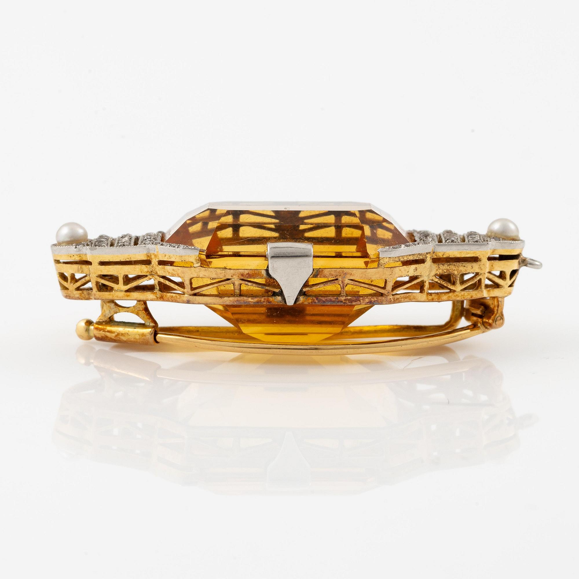 A brooch in 18K gold and platinum set with a faceted citrine.