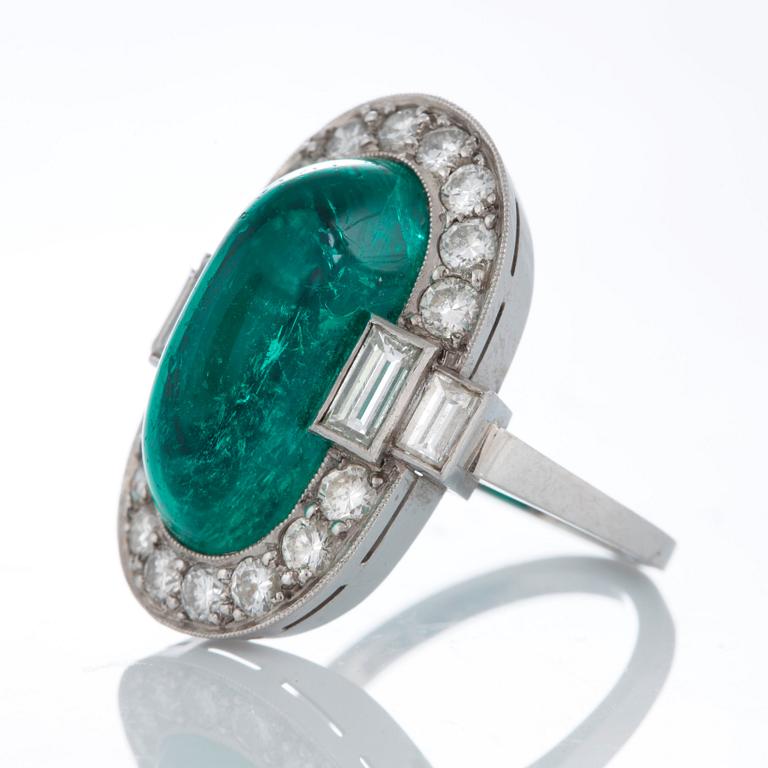 A platinum ring set with a cabochon-cut emerald ca 7 cts and brilliant and baguette-cut diamonds.