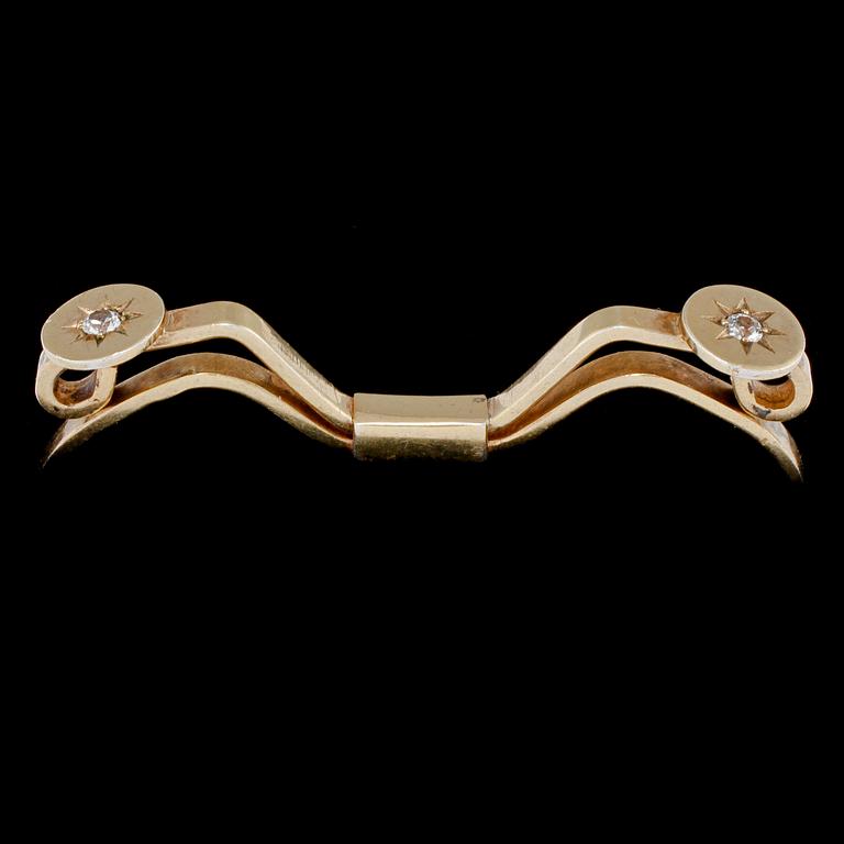 SPÄNNE, 18k guld med 2 briljantslipade vita stenar, Nils Ahlström, Borås, 1953. Vikt 6 g.